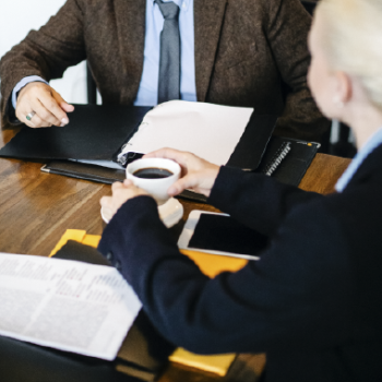 The School of Law and Political Science presents its research groups to the educational community and the general public. Photo taken from stock images showing two men gathered around a table reviewing documents, one of them holding a cup of coffee.