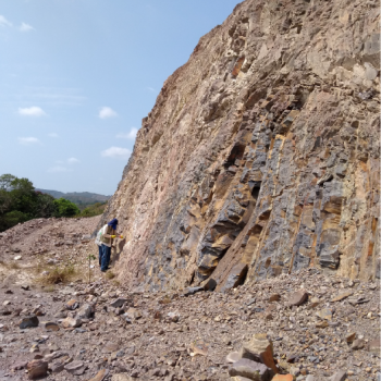 The School of Geology presents its research groups to the educational community and the general public. Photo provided by the school, general shot showing a person taking samples from the lower part of a mountain.