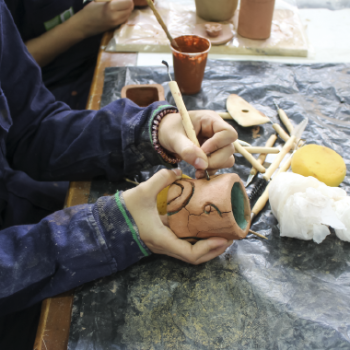 The School of Industrial Design presents its research groups to the educational community and the general public. Photo taken at the School of Industrial Design, close-up of the hands of a student, who is polishing a clay pot in the school's workshop.