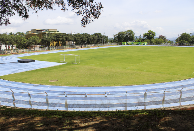 El Departamento de Deportes UIS invita a que se conozca su Estadio Primero de Marzo. Plano general del estadio donde aparece la cancha y la pista de atletismo.