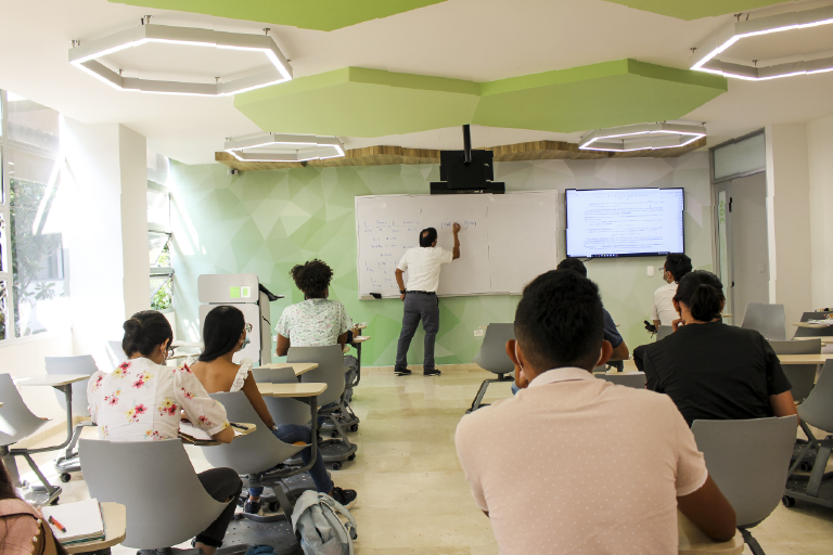The School of Mathematics invites you to get to know its Classroom 306, which is available to its students and the educational community. Photo taken at the School of Mathematics, general shot where students are seen from the back of the classroom receiving the class from a teacher.
