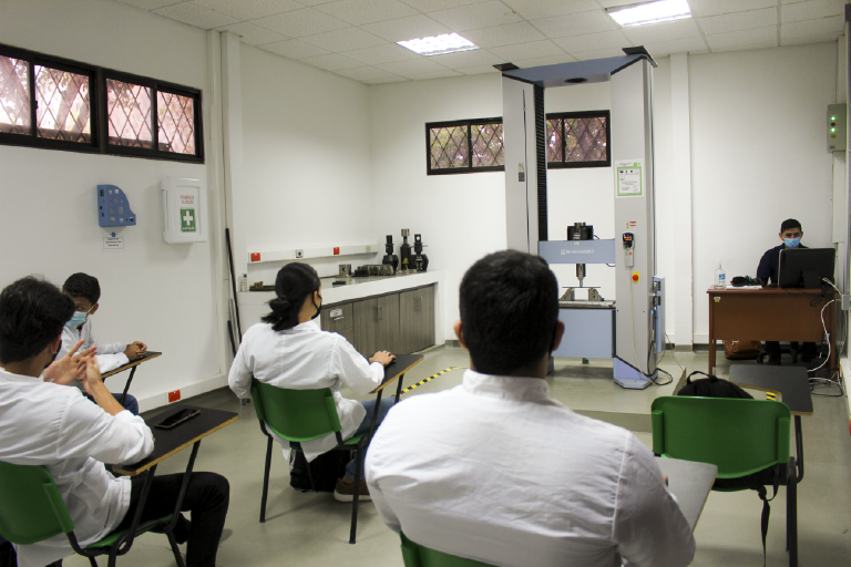 The School of Metallurgy and Materials Science invites you to get to know its Mechanical Testing Laboratory, which is at the disposal of its students and the educational community. Photo taken at the School, in a general shot of the room where several students are looking at a machine in the laboratory.