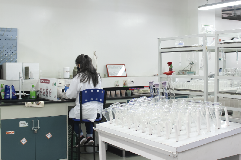 The School of Chemistry invites you to get to know its Soil Chemistry Laboratory, which is at the disposal of its students and the educational community. The photo was taken at the School of Chemistry, it is a general shot showing one of the members of this laboratory sitting with her back to a table, using laboratory equipment.